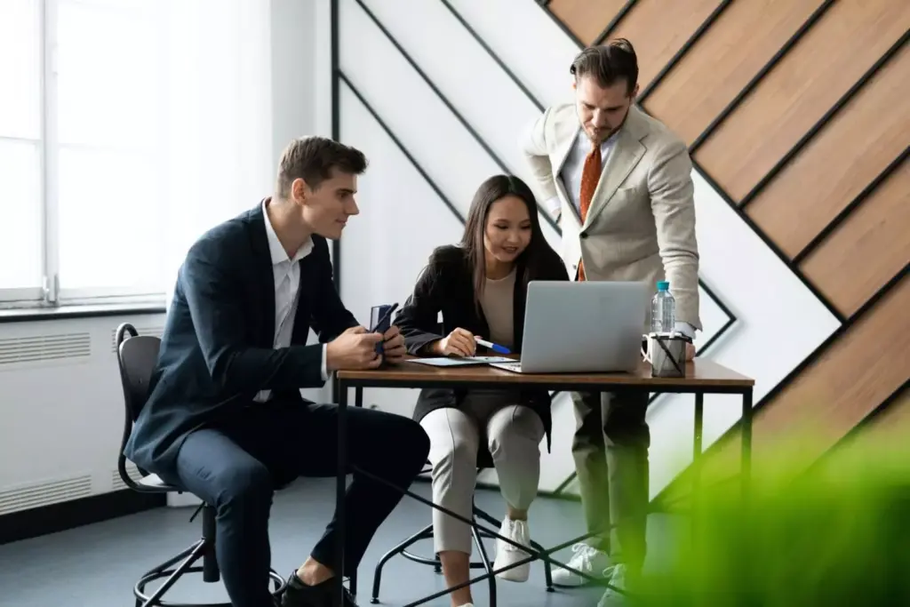 Professionals discussing documents beside a laptop